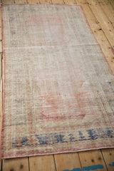 Distressed Oushak rug corner, worn pile showing foundation, red selvage, blue border.