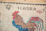 Distressed vintage Sparta pictorial rug: red rooster, 'HATIRA' text, ivory, and sapphire blue.