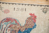 Pictorial detail of vintage distressed rug: 1981 date, rooster, and ivory field texture.