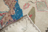 Folded corner of distressed Sparta rug showing ivory, blue, red pile and hand-knotted foundation.