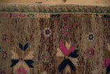 Distressed vintage Oushak rug, showing abrashed pile with magenta starburst and green wave border.