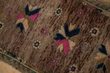Distressed Oushak rug showing fuchsia, blue pinwheel starburst on abrashed brown pile.