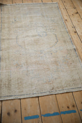 Low pile texture of distressed Oushak rug with faded cobalt blue vine motifs.