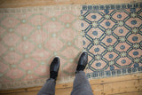 Distressed vintage Oushak runner showing significant dye lot shift; pink and blue trellis design.