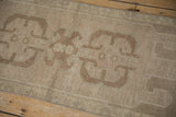 Distressed Oushak rug detail, showing muted beige geometric pattern, narrow border, and visible wear.