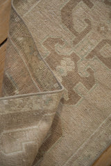 Distressed Oushak rug pile texture with muted beige tones and machine-bound edge.