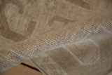 Textured beige pile of vintage distressed Oushak rug with even wear to knot heads.