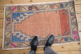 Distressed vintage Oushak rug runner with dusty rose prayer design, visible abrashes, and blue motifs.