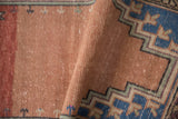 Distressed vintage Oushak rug pile featuring soft dusty rose tones and geometric blue border.