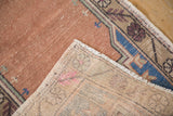 Distressed dusty rose Oushak rug pile contrasts with woven beige foundation and selvage.