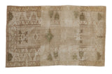Distressed vintage Melas rug features faded geometric medallions in muted beige and olive, 3'5