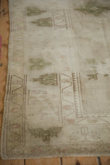 Vintage distressed Melas rug corner, showcasing intact side cord, soft olive and beige palette, and worn texture.