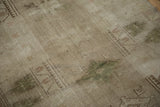 Distressed vintage Melas rug showing muted beige, olive geometric pattern, heavy abrashes, even wear.