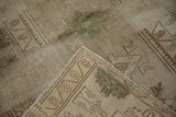 Folded corner of distressed vintage Melas rug showing geometric border and hand-knotted foundation.