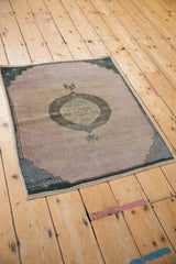 Distressed Oushak rug with abrashed mauve ground and dusty teal medallion.