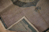 Vintage distressed Oushak rug corner displaying mauvish pile and reverse with woven teal selvage.