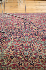 Intricate curvilinear floral and vine motifs on the tightly knotted purple and red Isfahan rug.