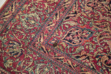 Intricate ruby, sapphire, and beige floral motifs on a vintage Isfahan rug corner, with small mark.
