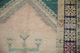 A close view of the prayer arch and geometric border on a vintage distressed Oushak rug.
