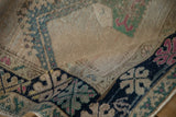 Folded corner of a vintage Oushak rug highlighting its distressed, low-pile texture and geometric border.