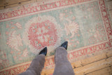 Distressed vintage Oushak rug with worn pile, revealing seafoam green and red motifs.