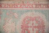 Vintage Oushak rug detail: seafoam green field, cherry red motifs, and areas of foundation showing.