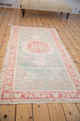 Distressed Oushak rug: cherry red and ivory side border, seafoam green field.