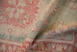 Textured fold of a distressed Oushak rug, with worn seafoam green, cherry red, ivory.