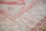 Expressive cloudband designs in faded red and ivory on a distressed vintage Turkish Oushak corner.