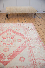 Distressed Oushak carpet with cherry red and ivory patterns styled in a room setting.