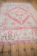 Angled view across a vintage Oushak carpet, highlighting its cloudband border and soft, worn texture.