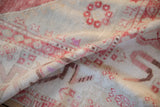 Softly folded vintage Oushak carpet revealing its low, worn pile and pale blush and red details.
