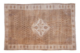 Distressed Oushak carpet with diamond medallion, subtle floral trellis, and muted ivory to pale brown tones.