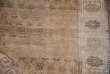 Distressed vintage Oushak rug, pale coffee brown trellis field and patterned ivory border with floral motifs.