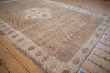 Distressed vintage Oushak rug with cream floral border and muted coffee brown field.