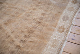 Vintage distressed Oushak carpet's ivory border, pale coffee brown arabesques, and natural fringe.