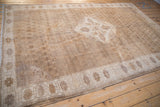 Distressed Oushak carpet corner showing pale coffee brown field and ivory floral border.