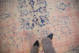 Distressed Oushak rug texture, showing worn dusty pink field and cobalt blue floral motifs.
