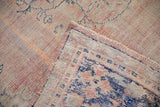 Distressed dusty pink pile with wear, folded to reveal cobalt blue palmette border on vintage Oushak rug.