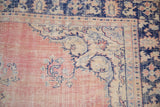 Distressed vintage Oushak carpet corner: worn dusty pink field, ivory spandrel, cobalt blue border.