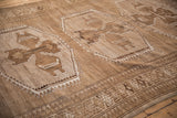 Distressed vintage Kars carpet detail showing geometric medallion, hook relief, and wave motif.