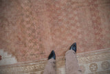 Oushak rug corner, abrash-softened copper lattice field, antique ivory wave border.