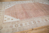 Faded copper lattice field meets ivory running wave border on distressed Oushak rug.