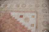 Close-up of distressed Oushak rug, pale copper field, ivory stepped border, coffee brown motifs.