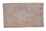 Vintage distressed Oushak rug with an oversized medallion in soft sandalwood, pale cantaloupe, and silver tones.