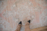 Close view showing the scale and low pile of a distressed Oushak rug in sandalwood and dusty rose.