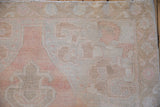 Low pile texture on the corner spandrel of a distressed Oushak rug in dusty rose and sand.