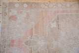 Corner spandrel detail on a distressed vintage Oushak rug with soft blush, sandalwood, and silver tones.