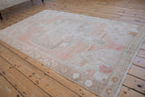 Angled view showing the full vintage Oushak rug's abrashed ground and soft pastel color palette.