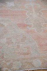 Angled close-up of the distressed Oushak rug's low pile and hand-knotted texture.